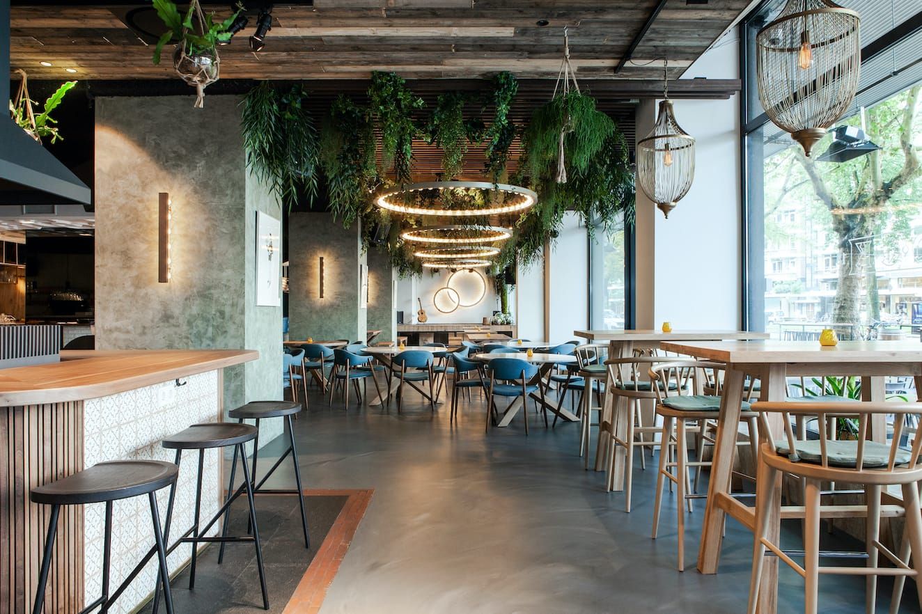 Brewpub room with hanging plants, ring lights and high wooden tables