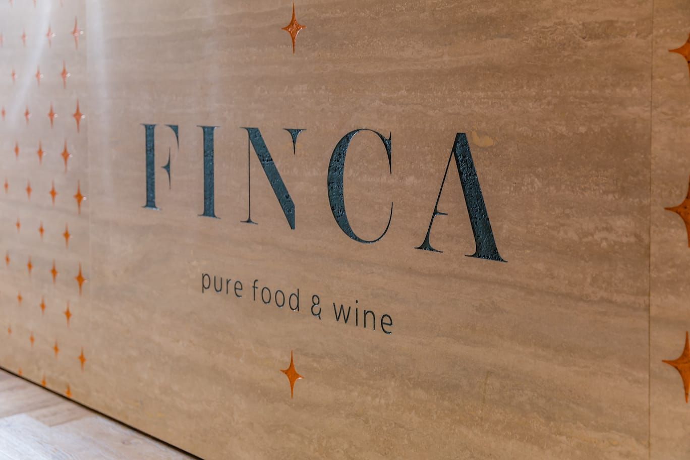 Finca logo and star pattern on a travertine-look bar front
