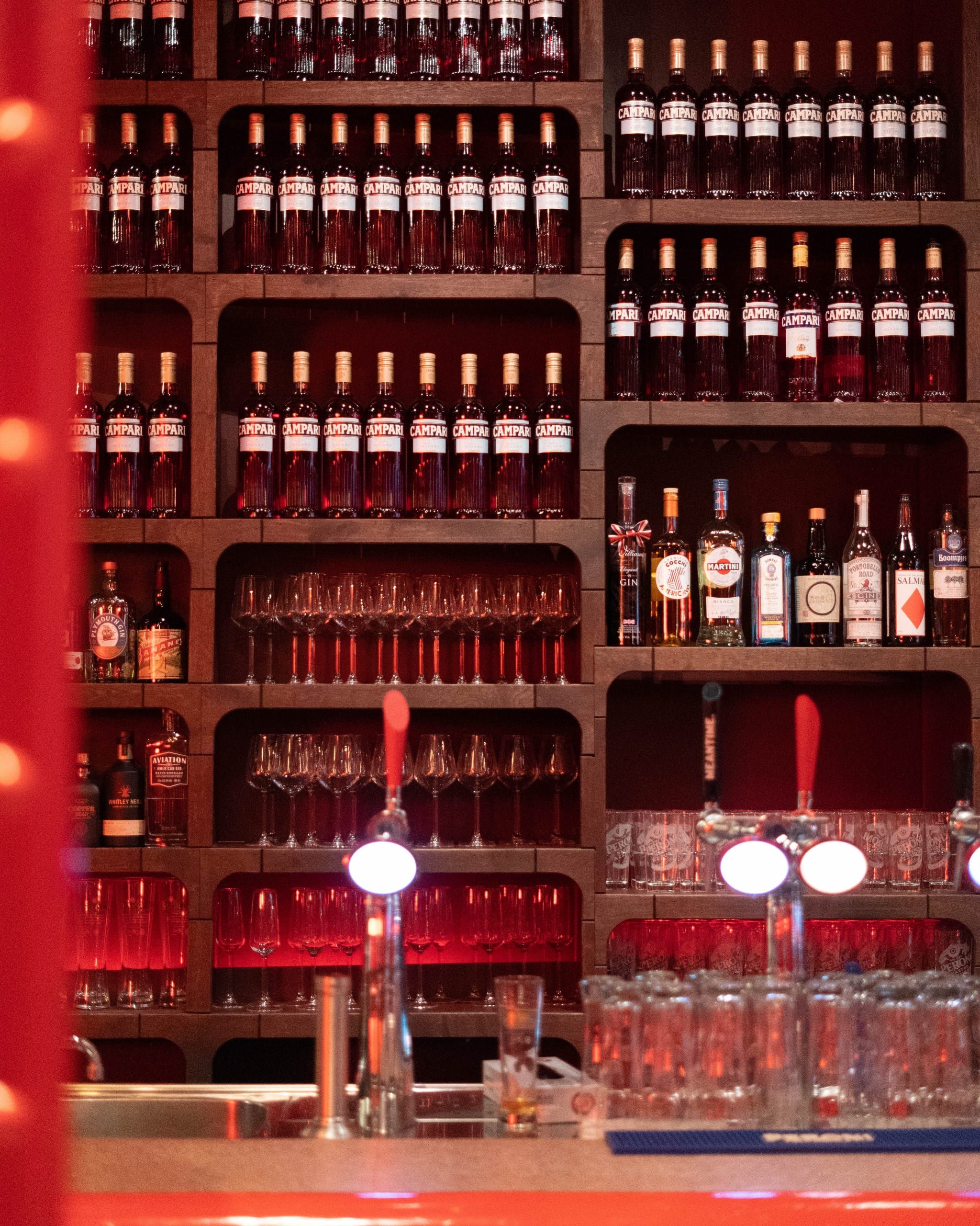 Backlit bar shelving stacked with bottles and glasses at Mamarazzi