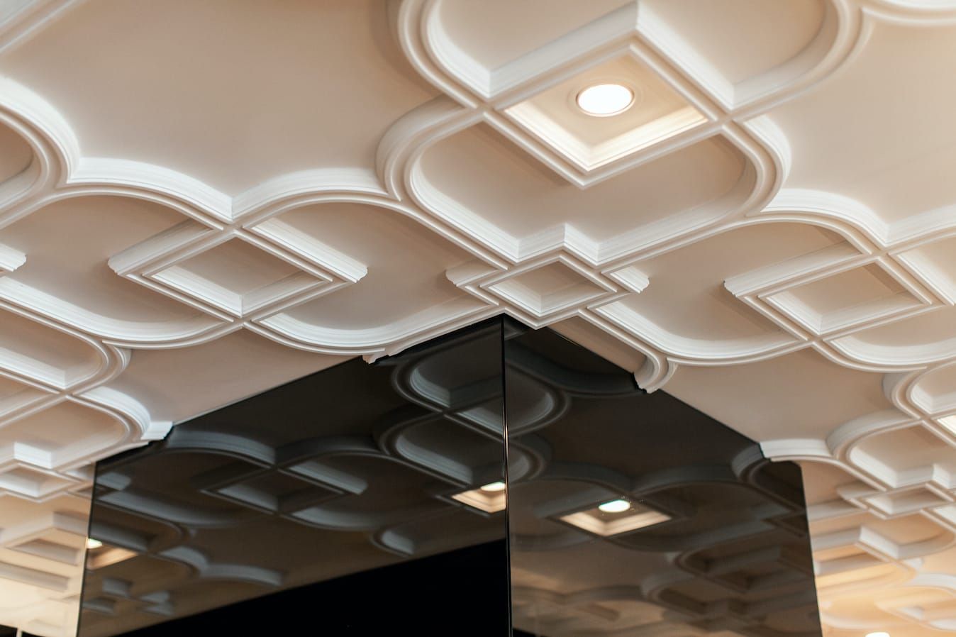 Ornate white plaster ceiling reflected in a dark mirror above the bar