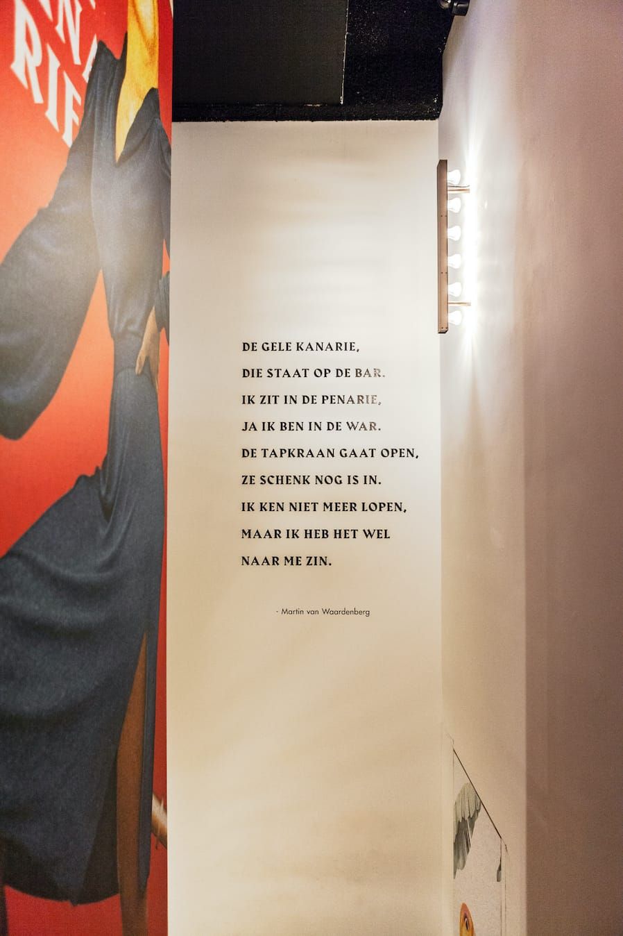 Wall poem in black type beside a mural and a bulb wall light