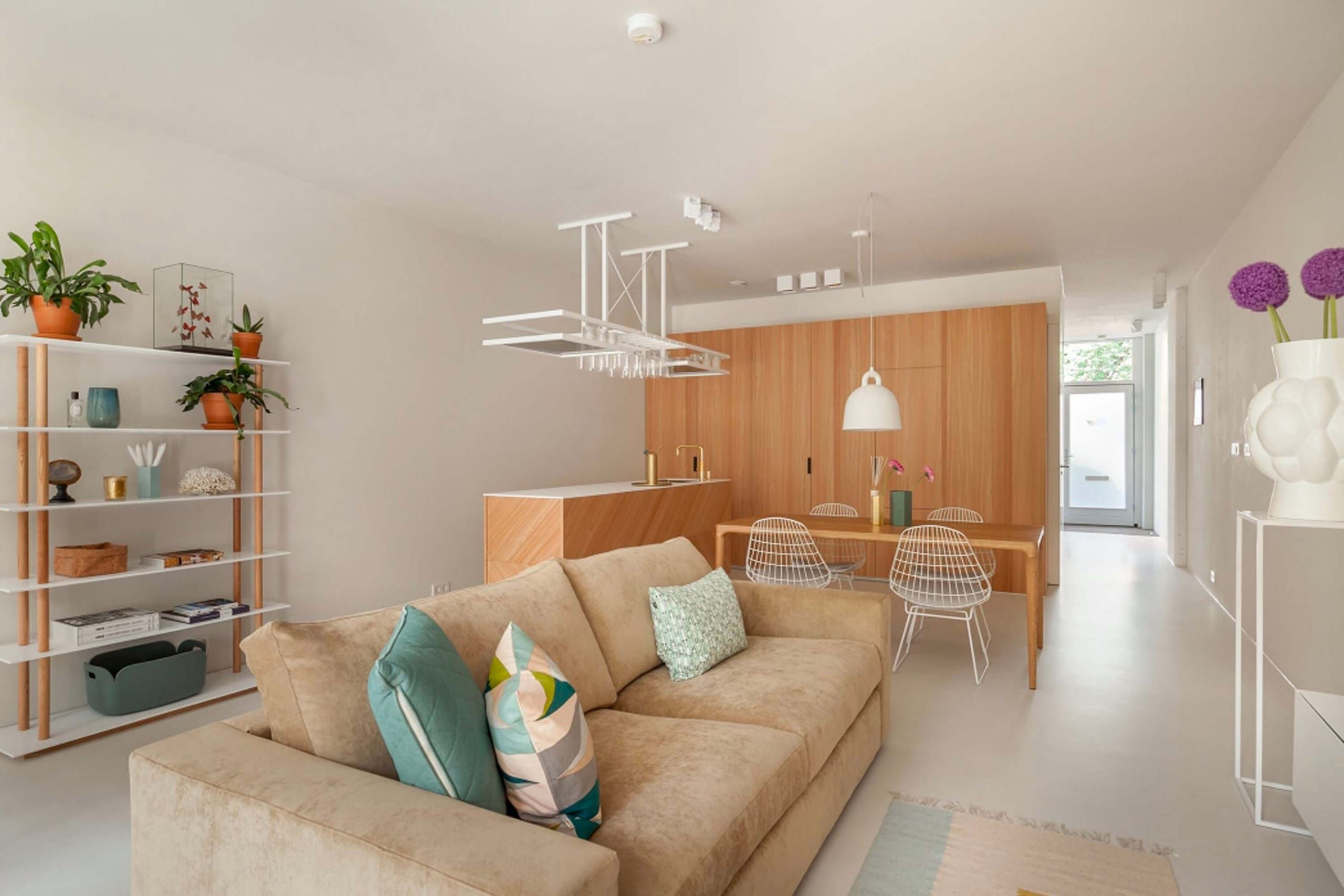 Sunshine living area with beige sofa, white shelving and an oak kitchen block beyond