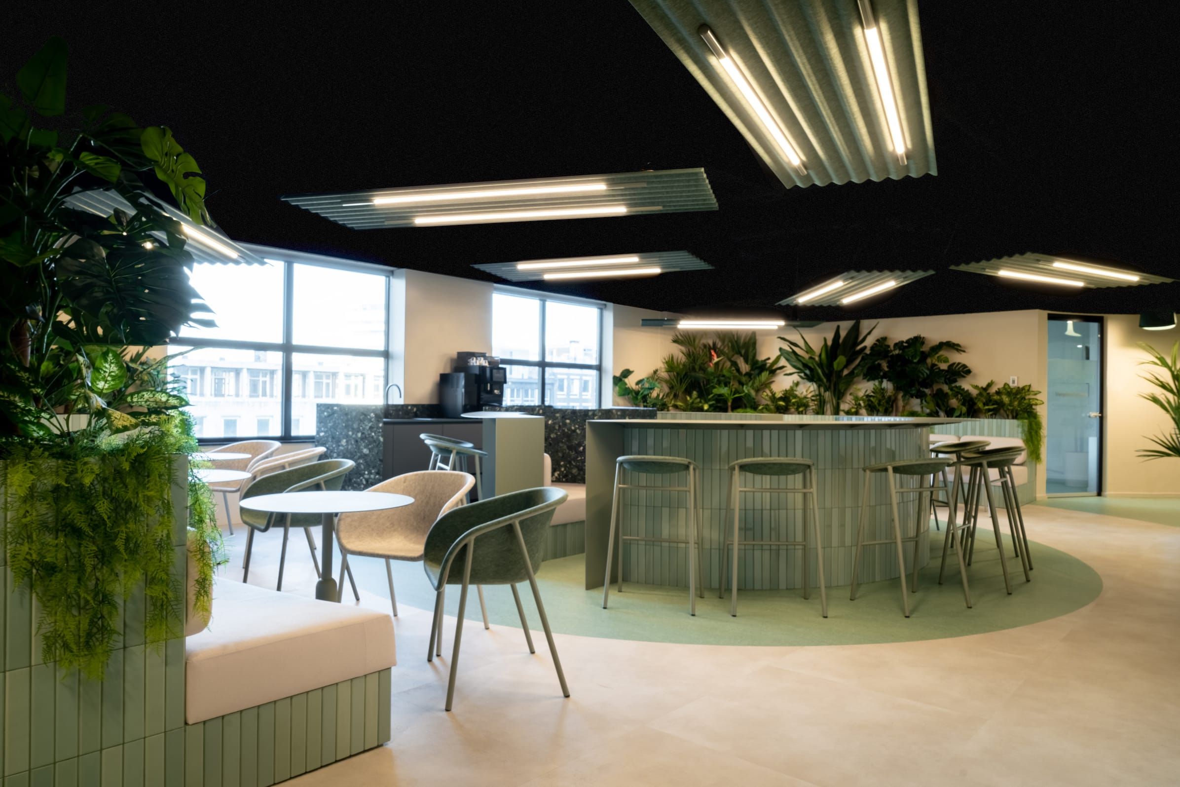 Pantry bar with green tiled counter, bar stools and planters in the Verdant office