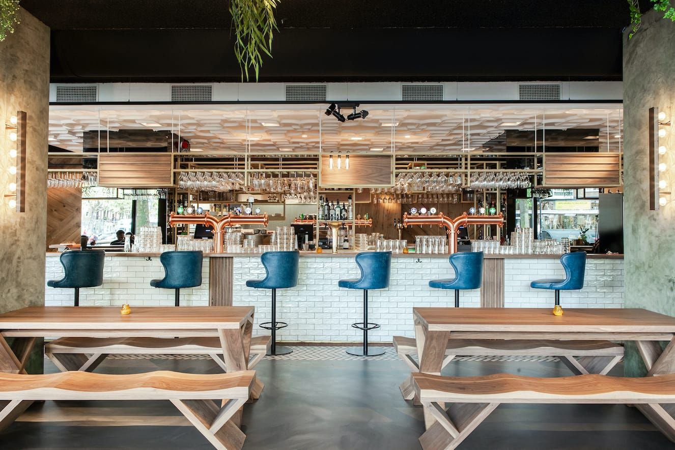 Bar with blue stools, white tiled front and copper taps at De Gele Kanarie