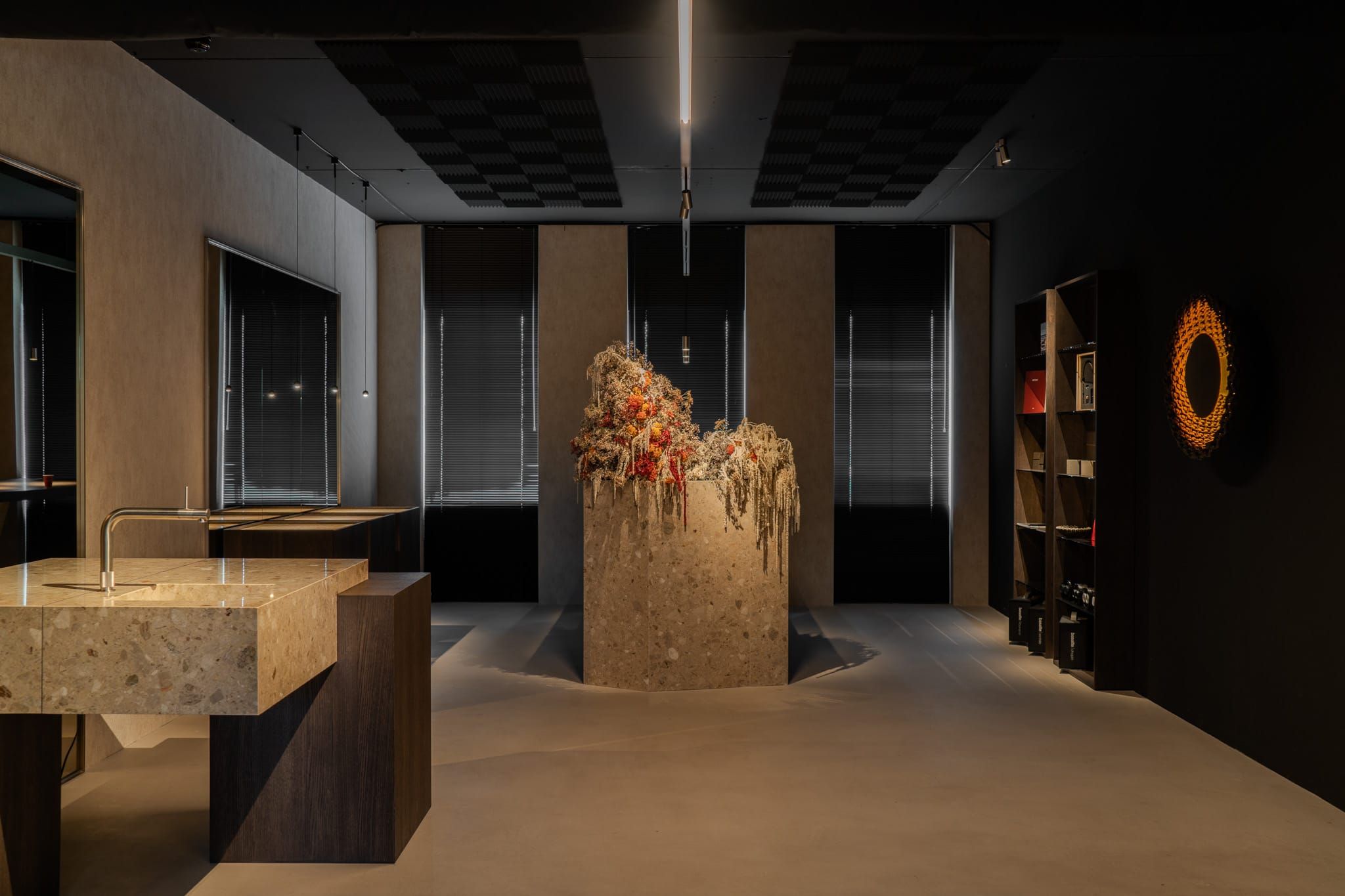 Showroom with a stone sink block, dried flower plinth and dark shelving in the Contrast Lighting office