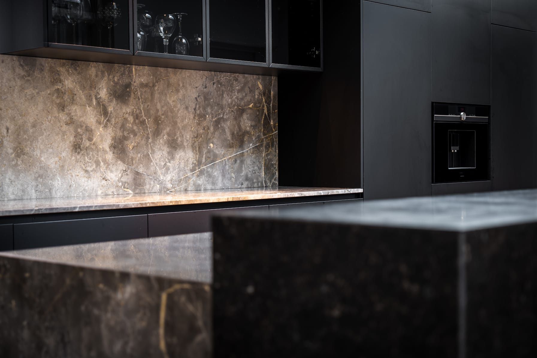Dark kitchen with stone backsplash, glass wall cabinets and oven in Interstellar